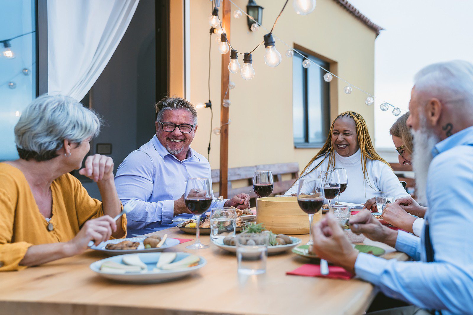 Diverse group of seniors dining together outside.